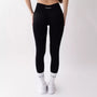 Leggings sportivi neri da donna indossati con fascia alta in vita, morbidi ed elasticizzati.
