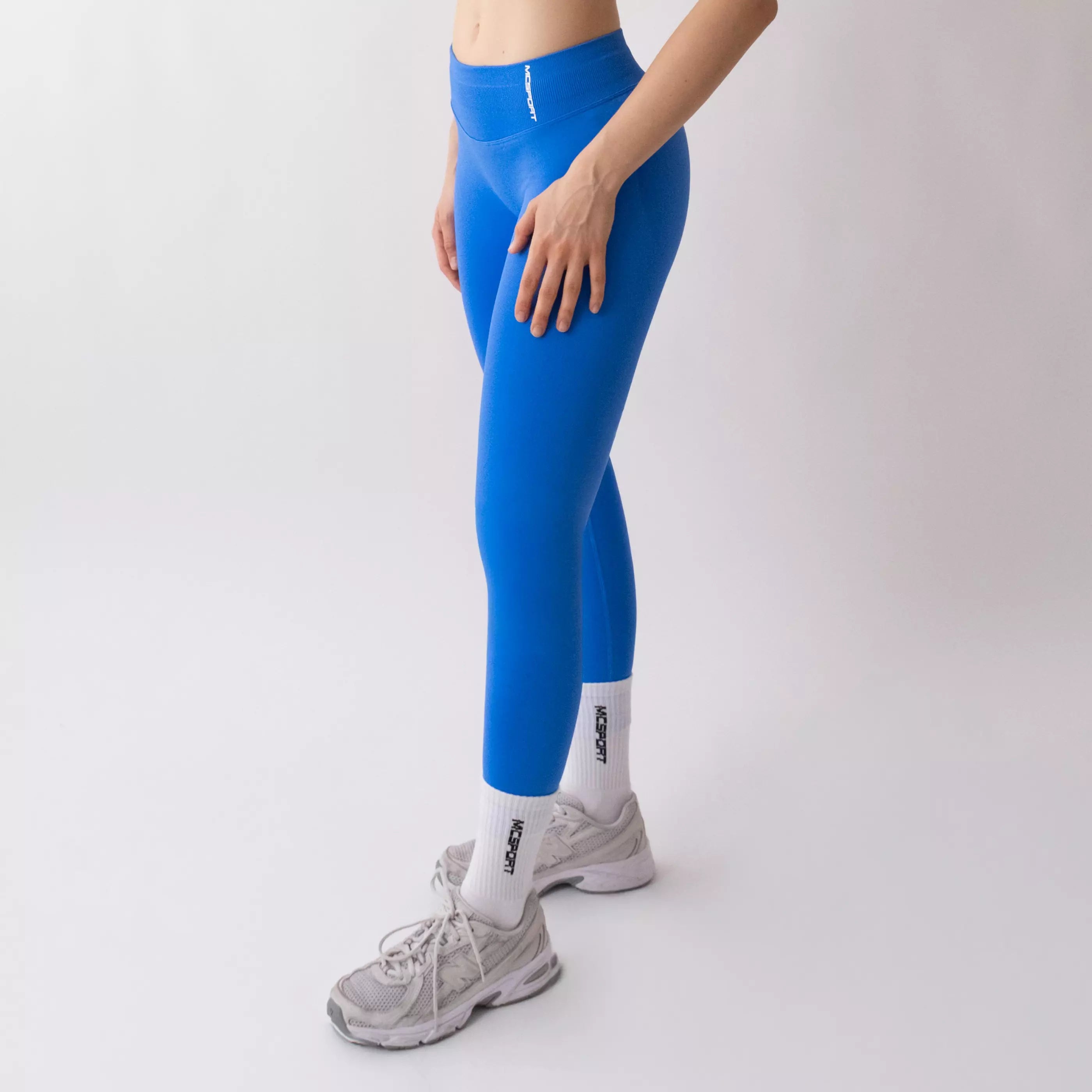 Leggings sportivi blu da donna indossati con fascia alta in vita, morbidi ed elasticizzati.