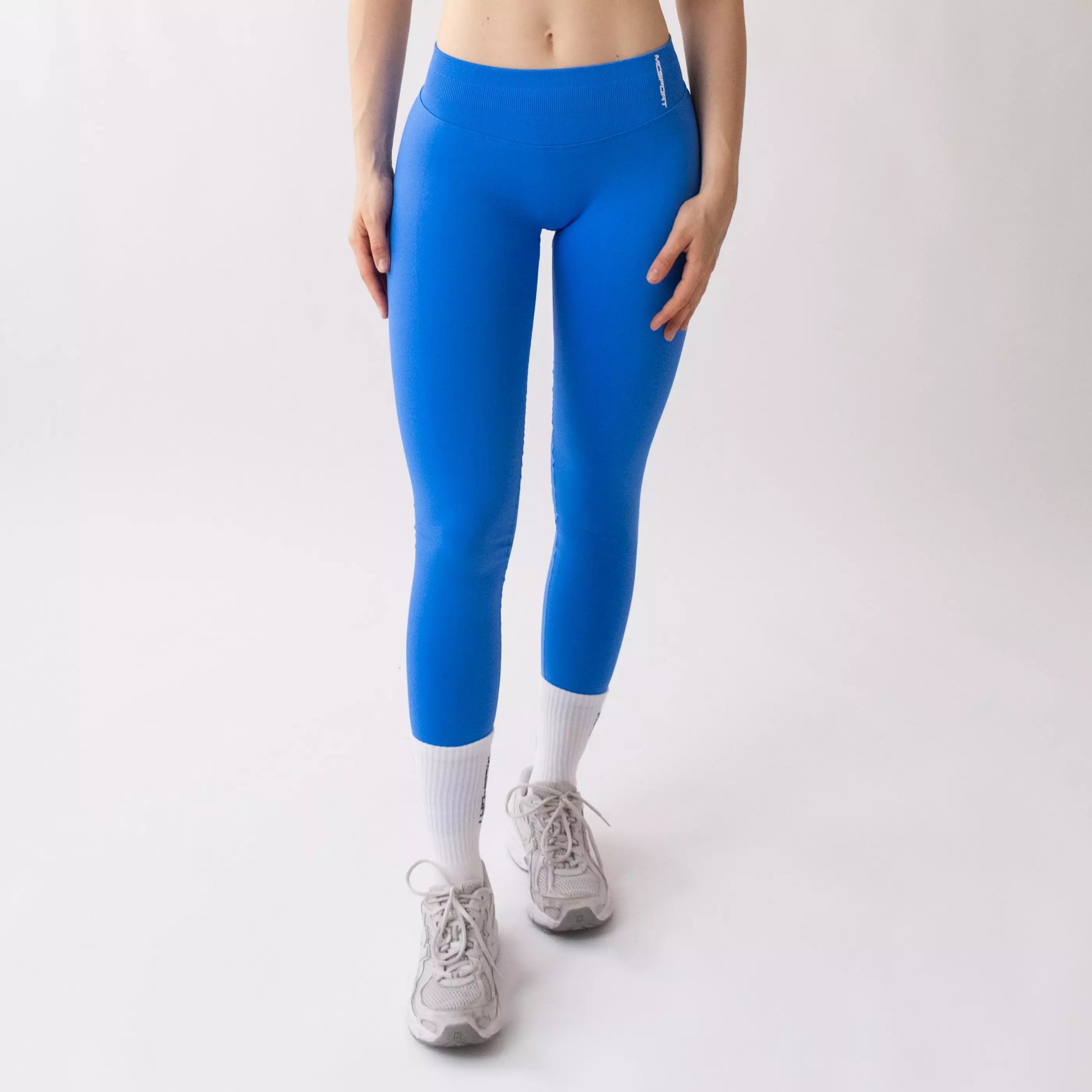 Leggings sportivi blu da donna indossati con fascia alta in vita, morbidi ed elasticizzati.