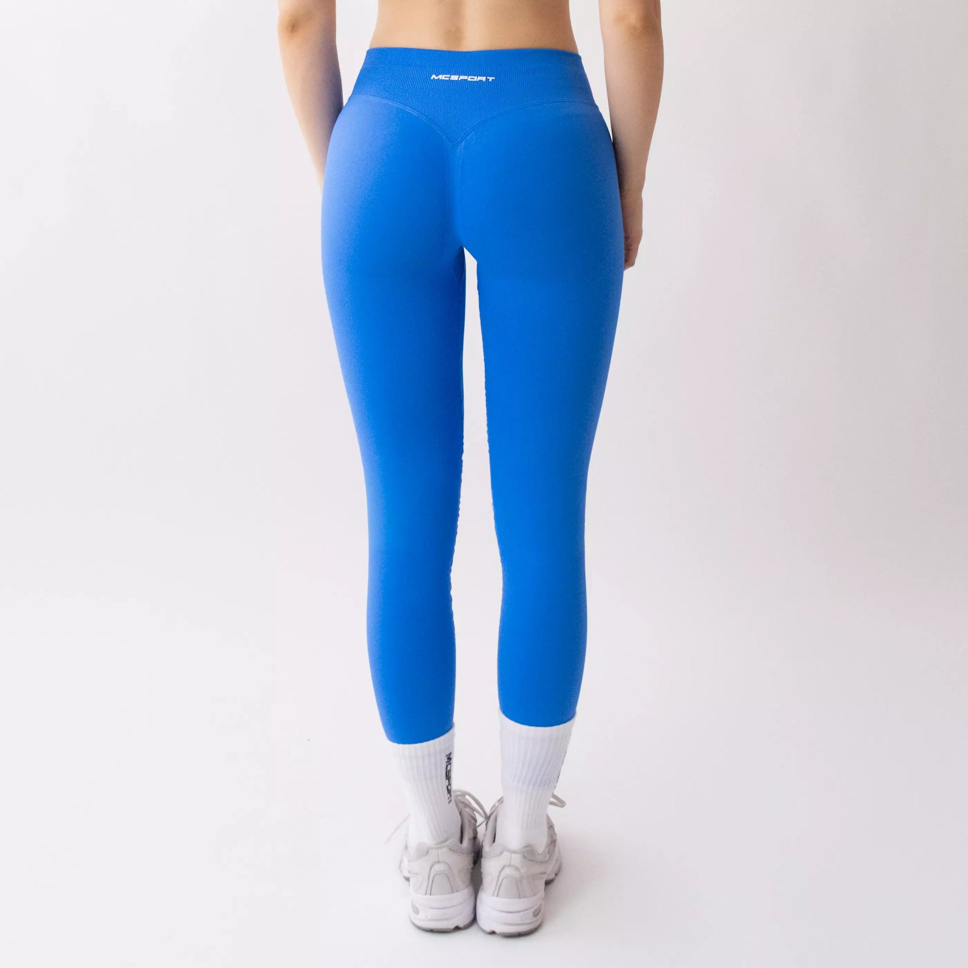 Leggings sportivi blu da donna indossati con fascia alta in vita, morbidi ed elasticizzati.