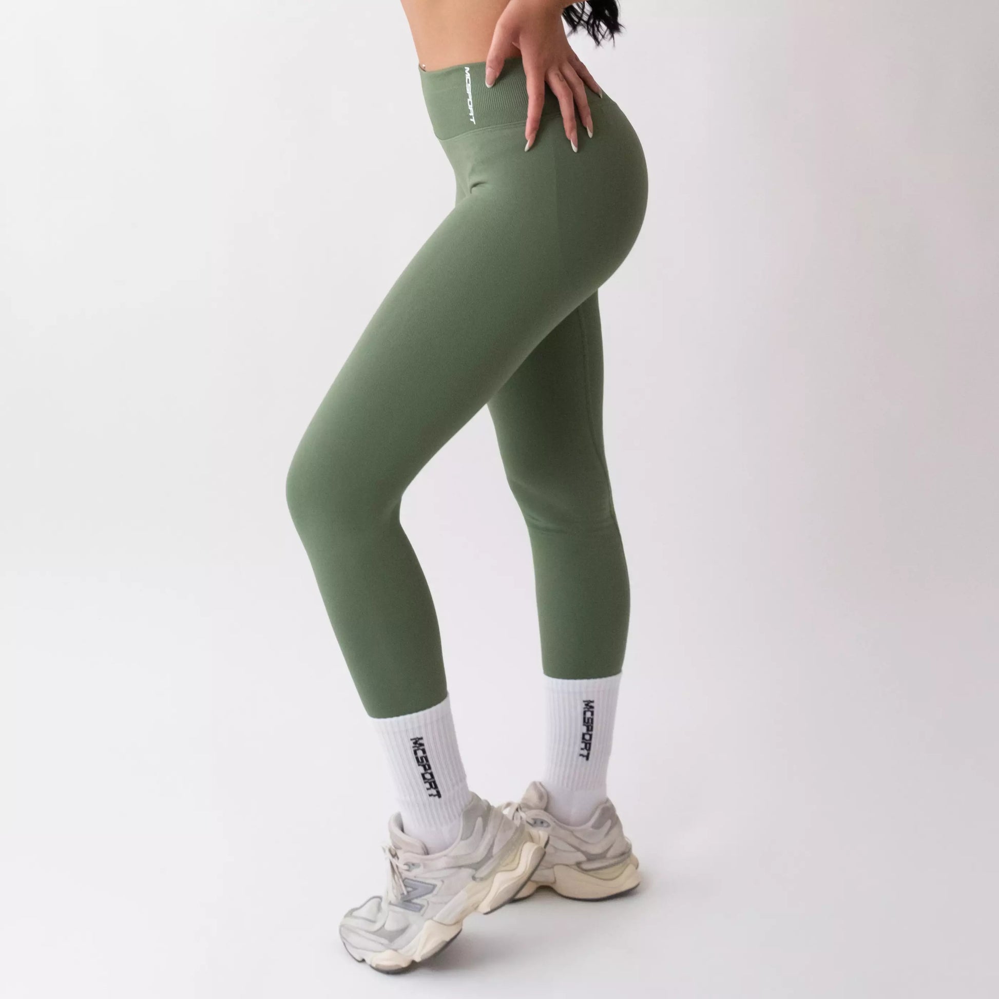 Leggings sportivi verde salvia da donna indossati con fascia alta in vita, morbidi ed elasticizzati.
