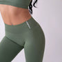 Dettaglio leggings sportivi verde salvia da donna indossati con fascia alta in vita, morbidi ed elasticizzati.