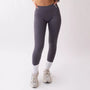 Leggings sportivi grigi da donna indossati con fascia alta in vita, morbidi ed elasticizzati.