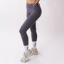 Leggings sportivi grigi da donna indossati con fascia alta in vita, morbidi ed elasticizzati.