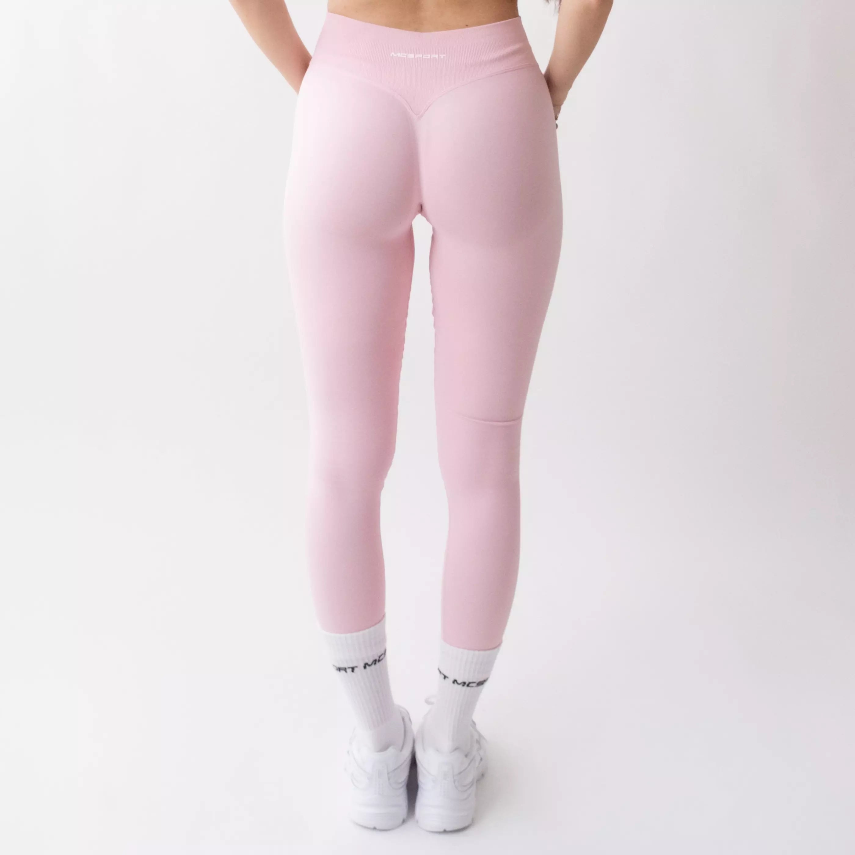 Leggings sportivi rosa da donna indossati con fascia alta in vita, morbidi ed elasticizzati.