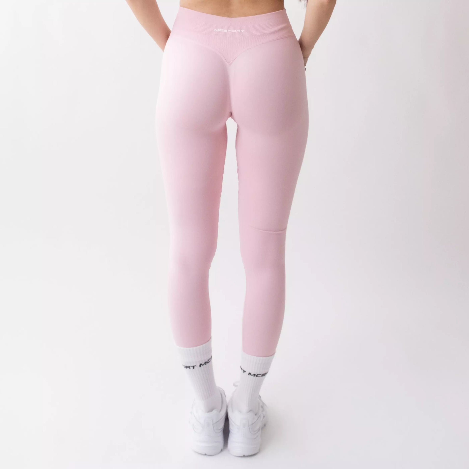Leggings sportivi rosa da donna indossati con fascia alta in vita, morbidi ed elasticizzati.