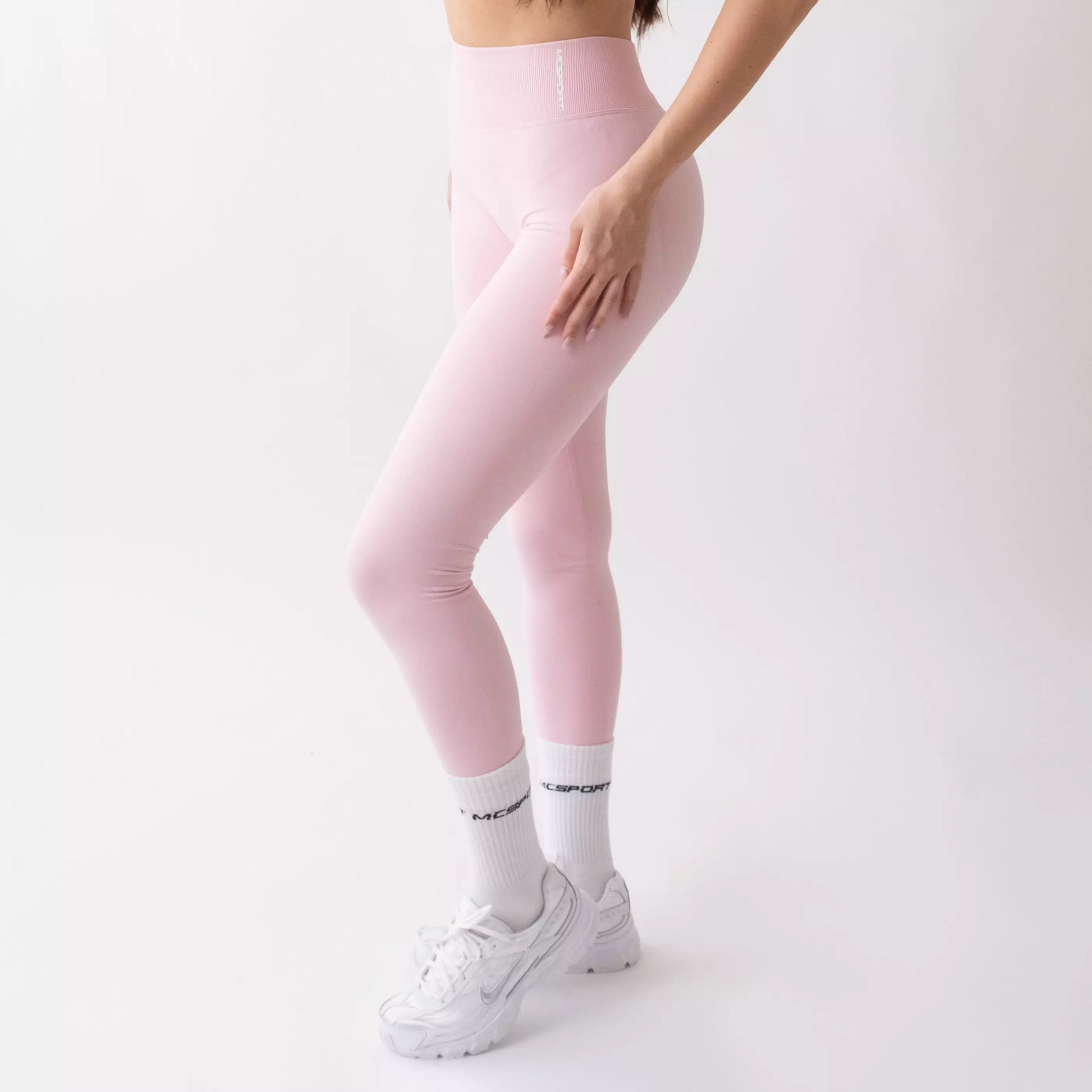 Leggings sportivi rosa da donna indossati con fascia alta in vita, morbidi ed elasticizzati.