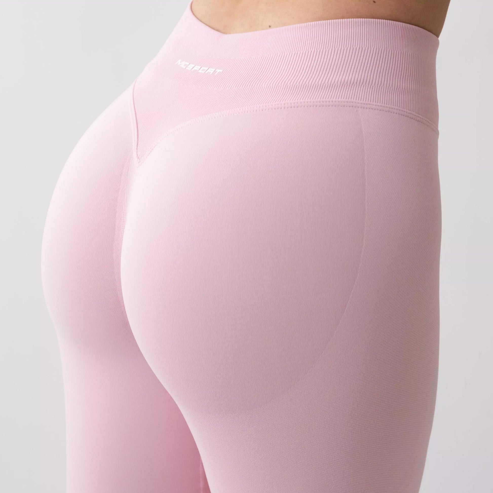 Dettaglio leggings sportivi rosa da donna indossati con fascia alta in vita, morbidi ed elasticizzati.