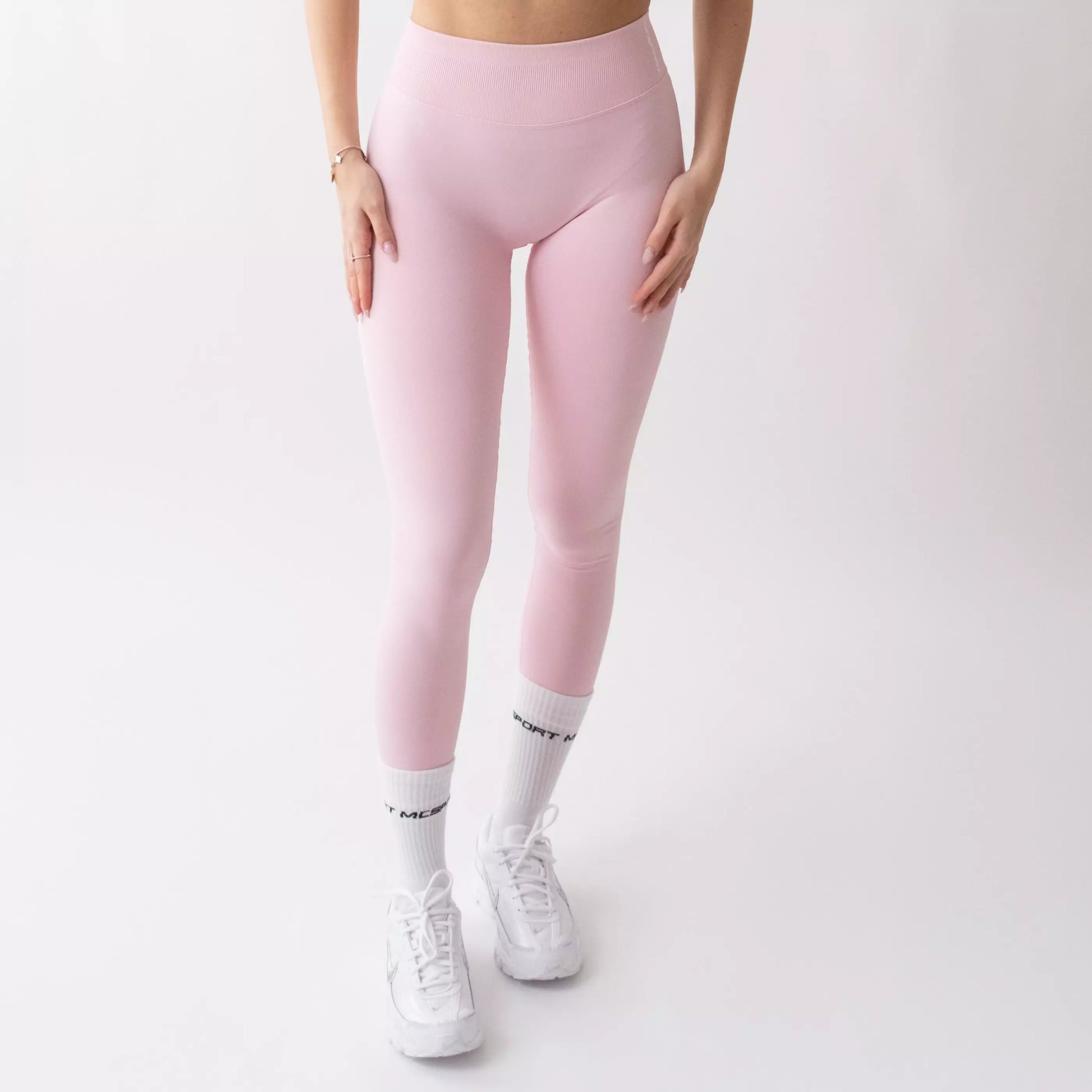 Leggings sportivi rosa da donna indossati con fascia alta in vita, morbidi ed elasticizzati.