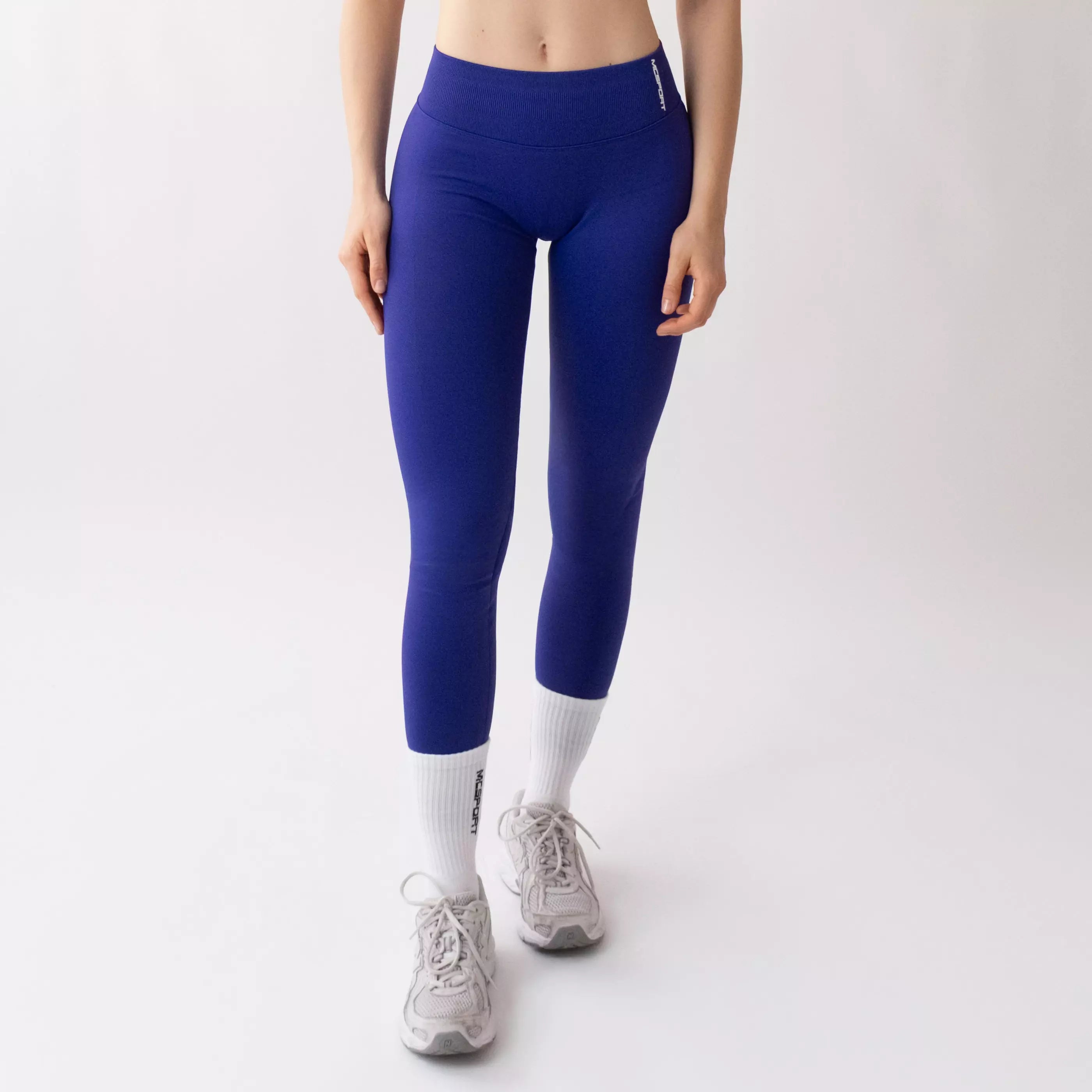 Leggings sportivi viola da donna indossati con fascia alta in vita, morbidi ed elasticizzati.