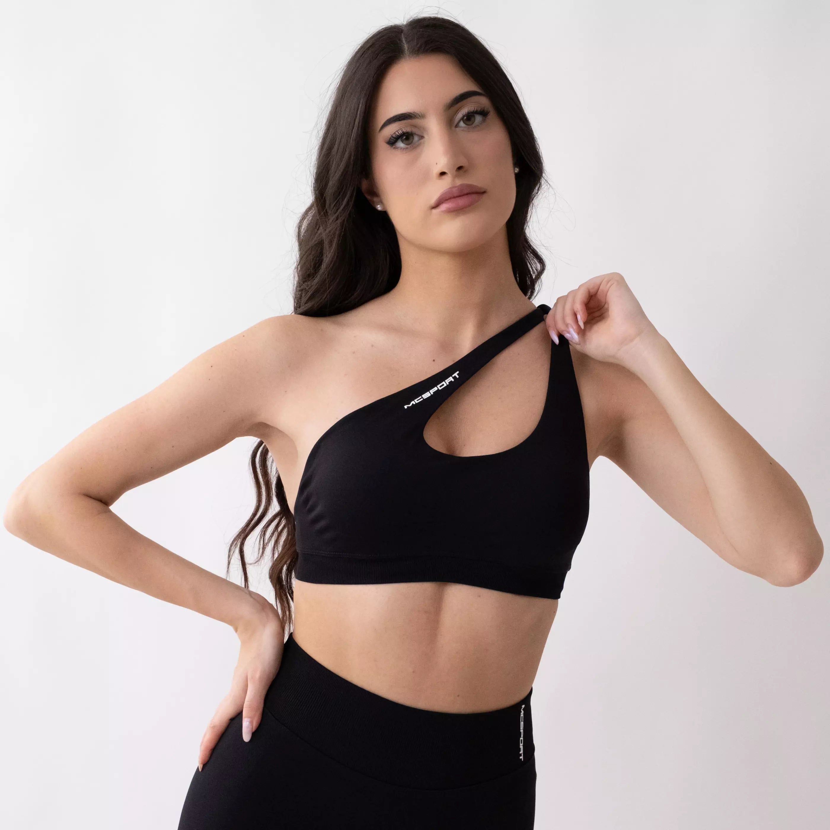 Top sportivo monospalla nero da donna indossato dal design moderno ed essenziale, con supporto confortevole e tessuto elasticizzato. 
