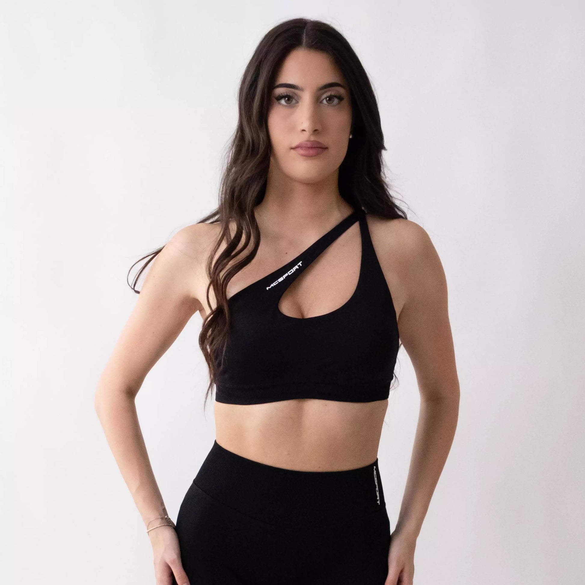 Top sportivo monospalla nero da donna indossato dal design moderno ed essenziale, con supporto confortevole e tessuto elasticizzato. 