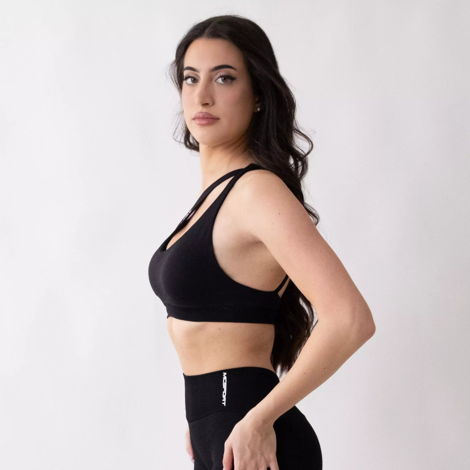 Top sportivo monospalla nero da donna indossato dal design moderno ed essenziale, con supporto confortevole e tessuto elasticizzato. 