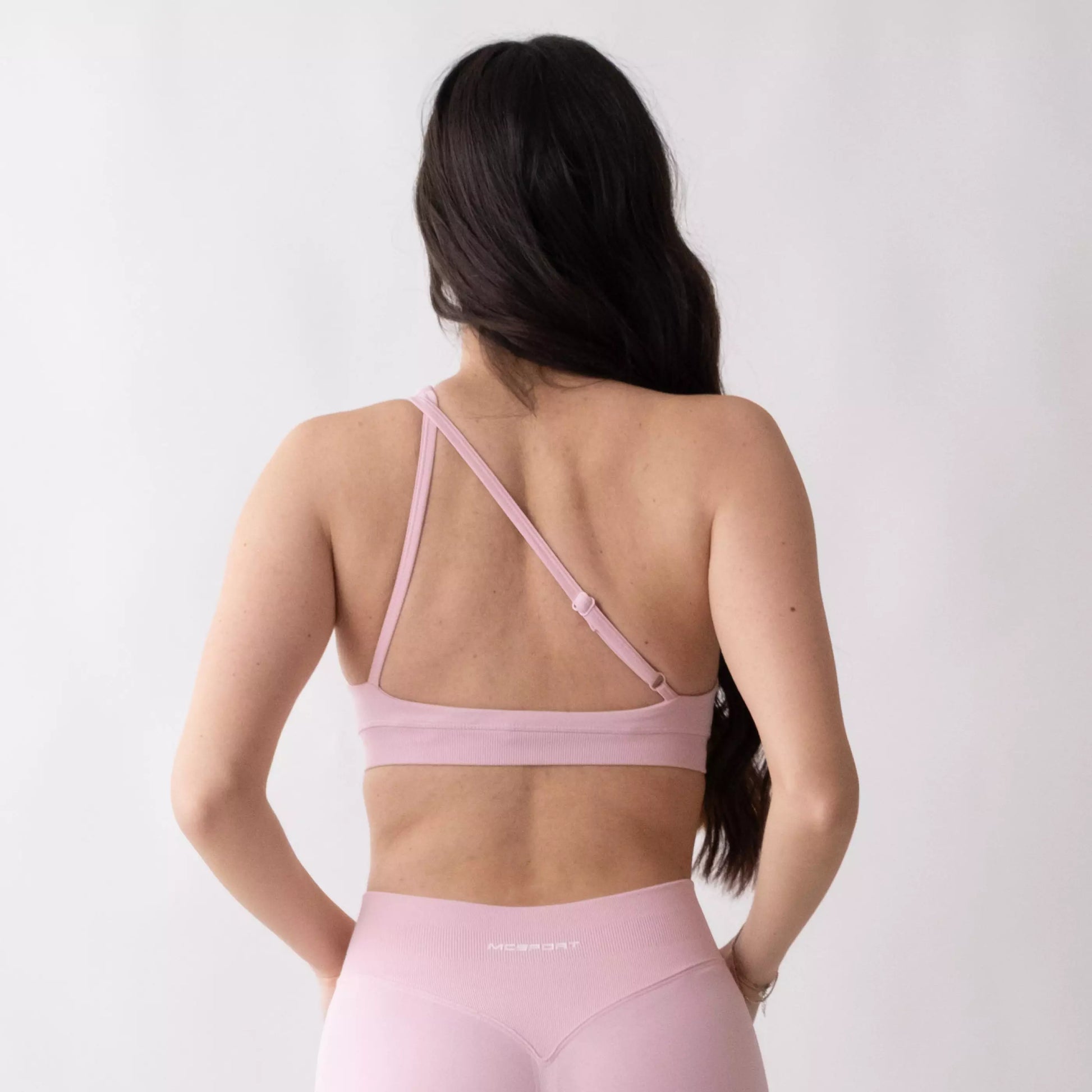 Top sportivo monospalla nero da donna indossato dal design moderno ed essenziale, con supporto confortevole e tessuto elasticizzato. Ideale per fitness, yoga, pilates e allenamenti.