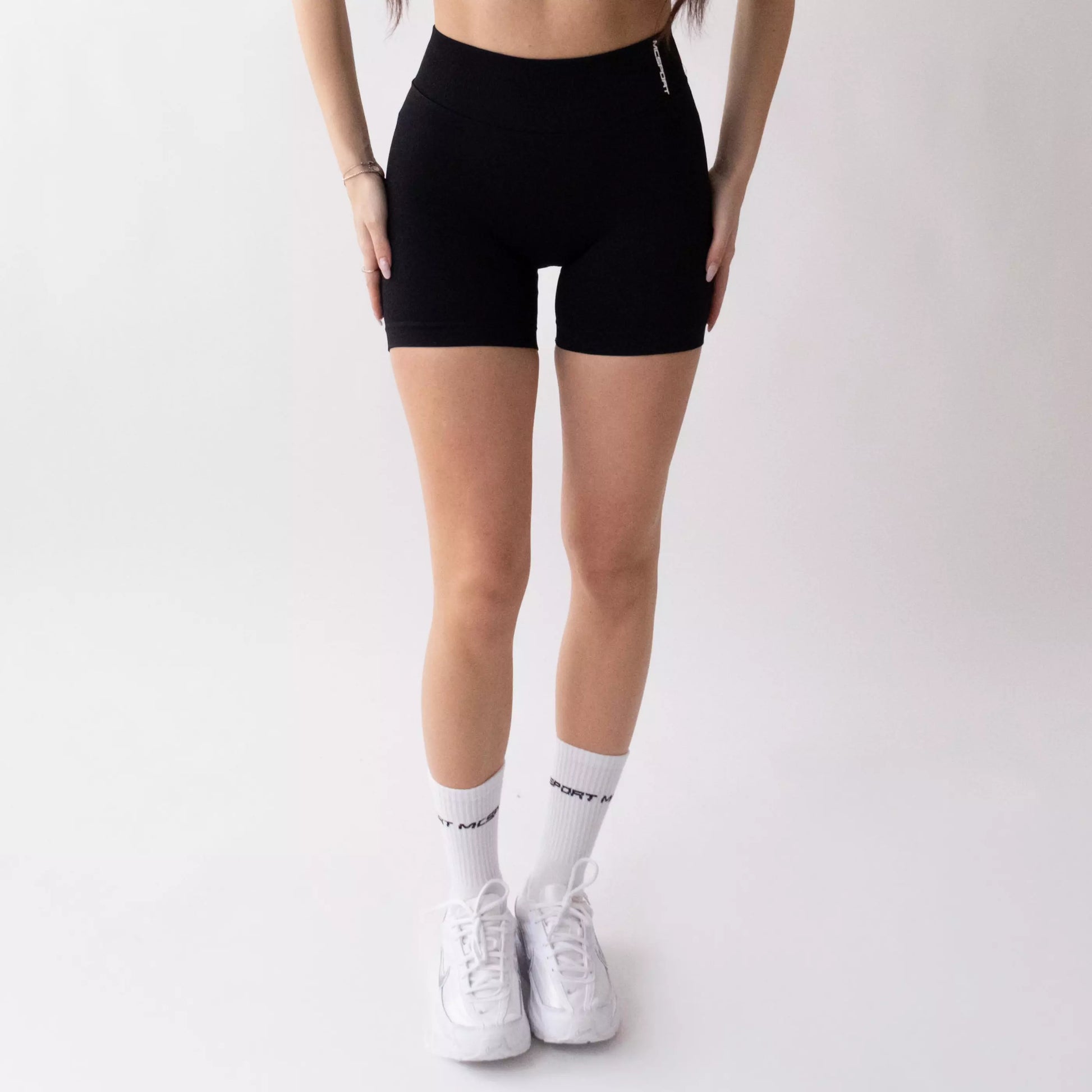 Shorts sportivi neri da donna indossati con fascia alta in vita, morbidi ed elasticizzati.