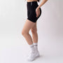 Shorts sportivi neri da donna indossati con fascia alta in vita, morbidi ed elasticizzati.