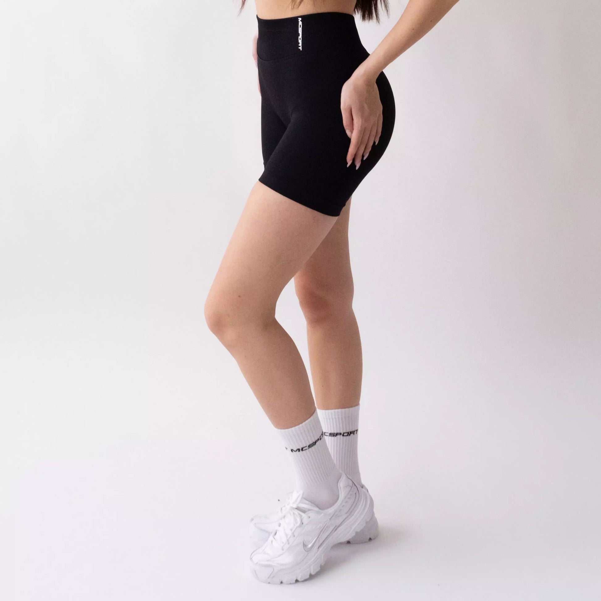 Shorts sportivi neri da donna indossati con fascia alta in vita, morbidi ed elasticizzati.