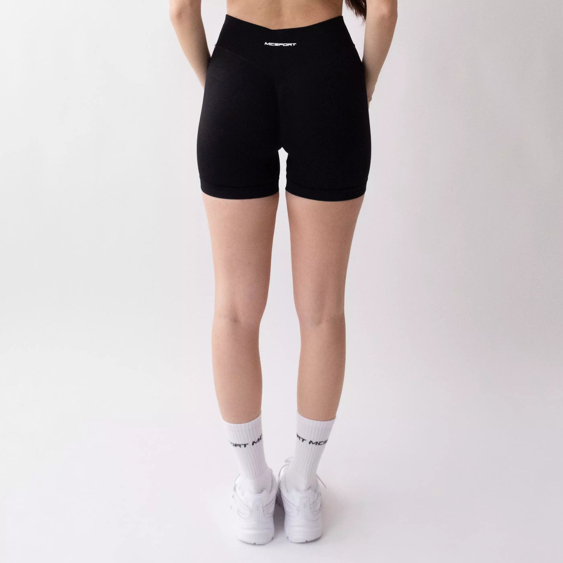 Shorts sportivi neri da donna indossati con fascia alta in vita, morbidi ed elasticizzati.
