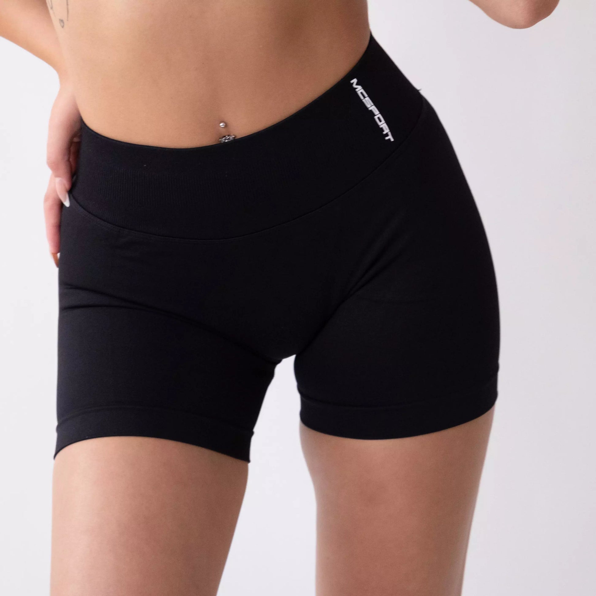Shorts sportivi neri da donna indossati con fascia alta in vita, morbidi ed elasticizzati.