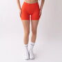 Shorts sportivi color corallo da donna indossati con fascia alta in vita, morbidi ed elasticizzati.