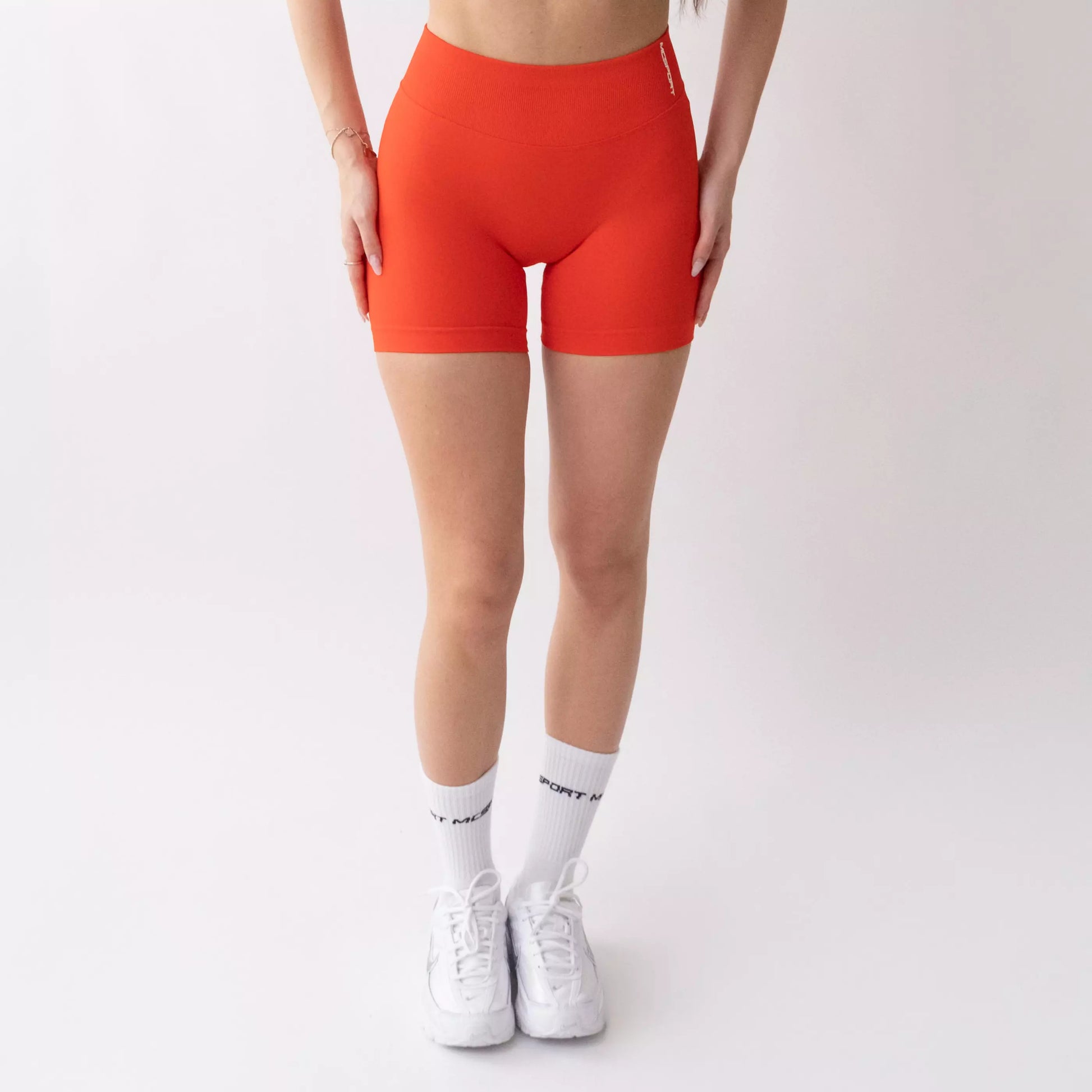 Shorts sportivi color corallo da donna indossati con fascia alta in vita, morbidi ed elasticizzati.