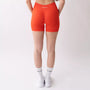 Shorts sportivi color corallo da donna indossati con fascia alta in vita, morbidi ed elasticizzati.