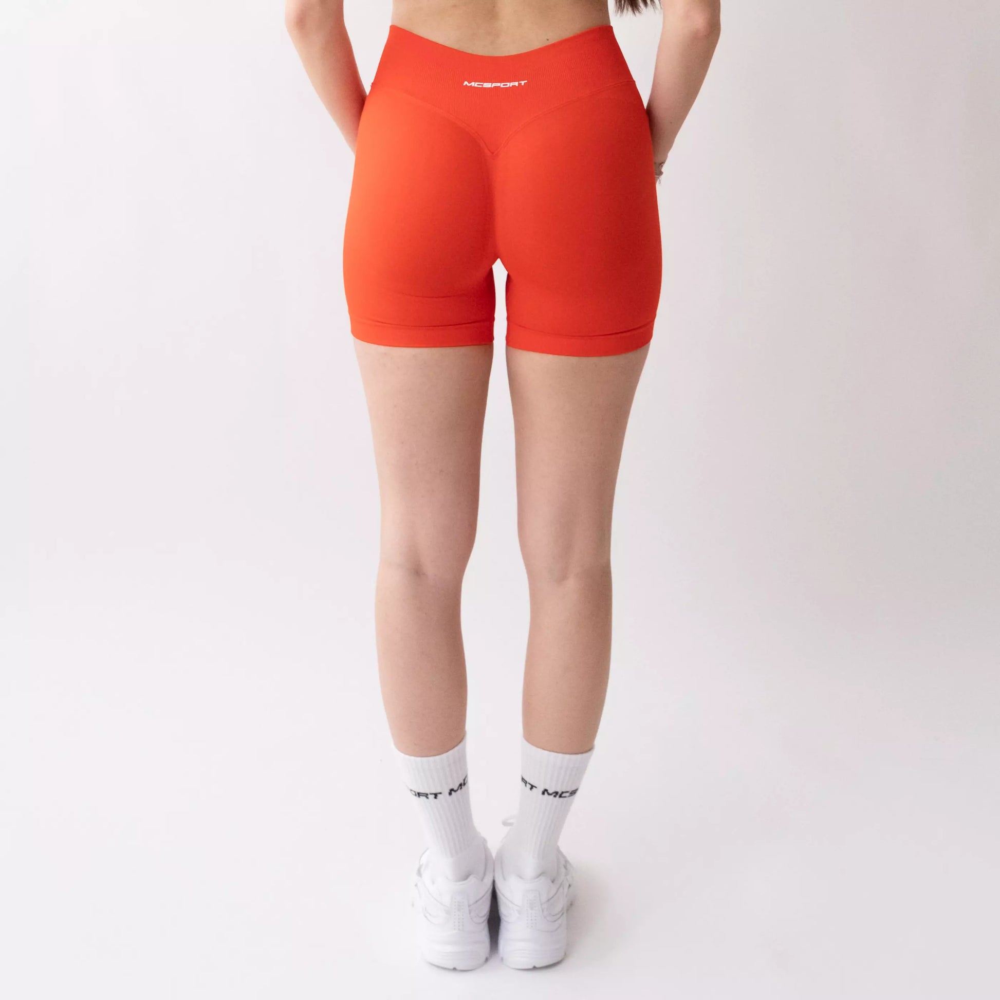 Shorts sportivi color corallo da donna indossati con fascia alta in vita, morbidi ed elasticizzati.
