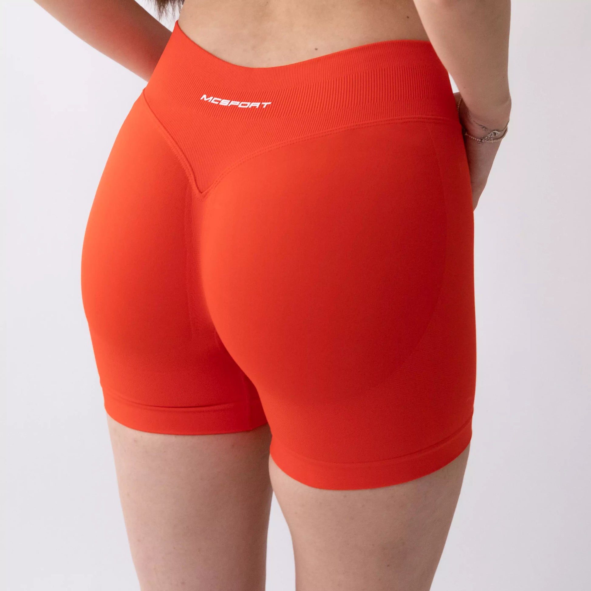 Shorts sportivi color corallo da donna indossati con fascia alta in vita, morbidi ed elasticizzati.