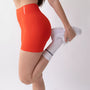 Shorts sportivi color corallo da donna indossati con fascia alta in vita, morbidi ed elasticizzati.