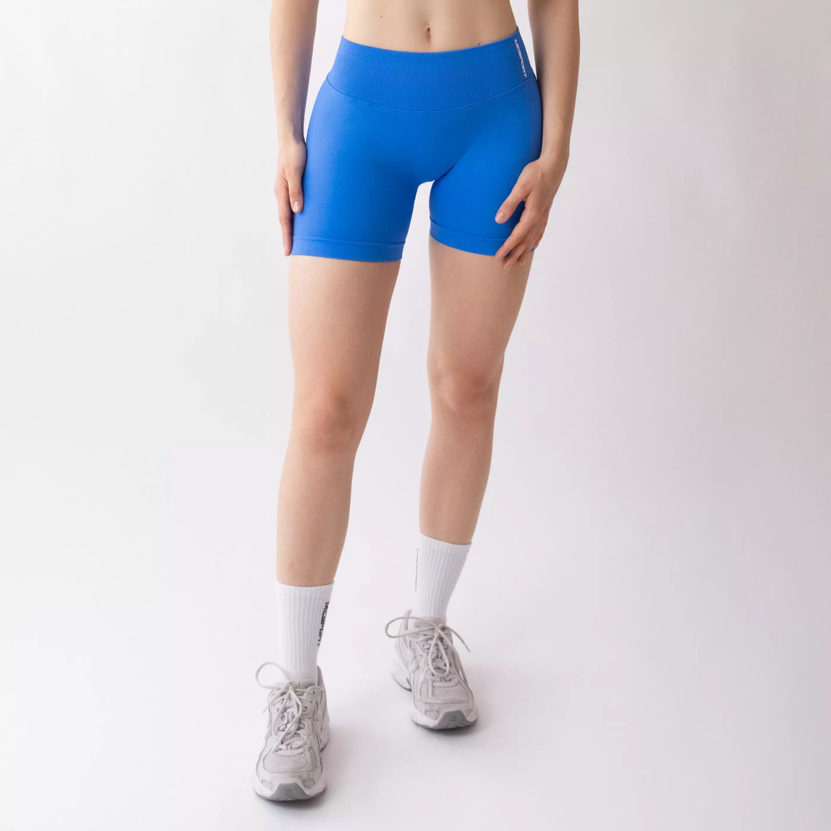 Shorts sportivi blu da donna indossati con fascia alta in vita, morbidi ed elasticizzati.