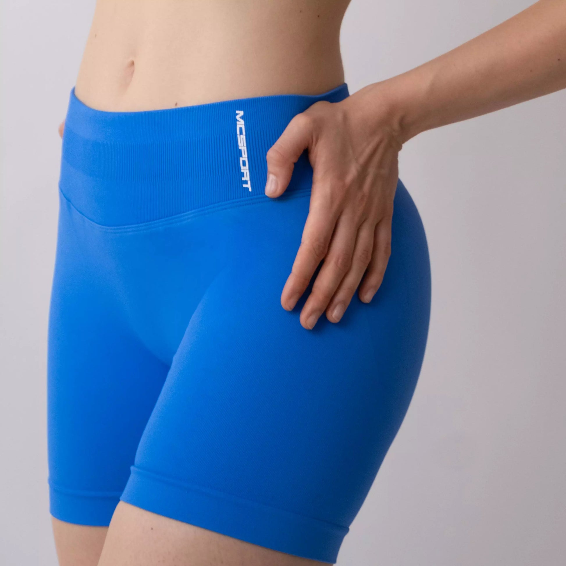 Shorts sportivi blu da donna indossati con fascia alta in vita, morbidi ed elasticizzati.