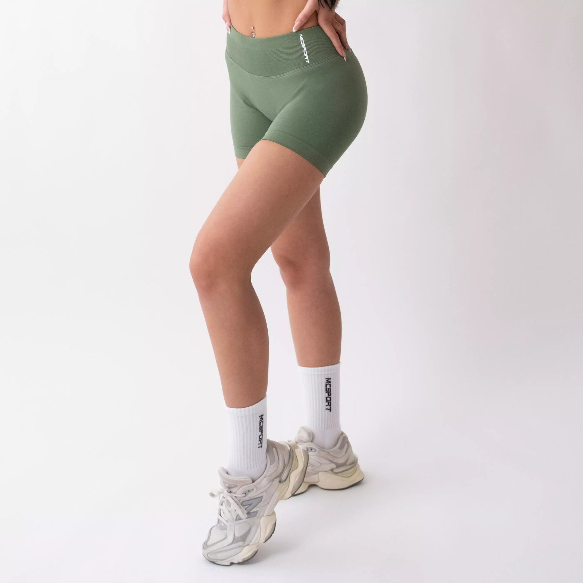 Shorts sportivi verde salvia da donna indossati con fascia alta in vita, morbidi ed elasticizzati.