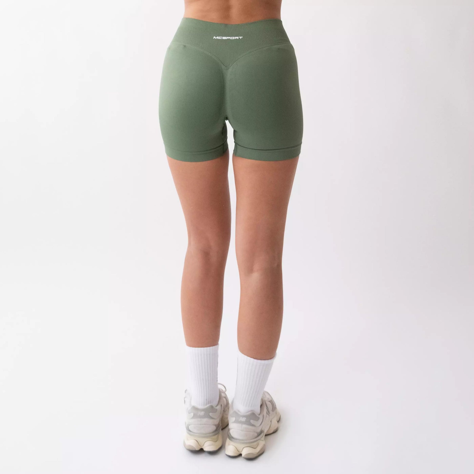 Shorts sportivi verde salvia da donna indossati con fascia alta in vita, morbidi ed elasticizzati.