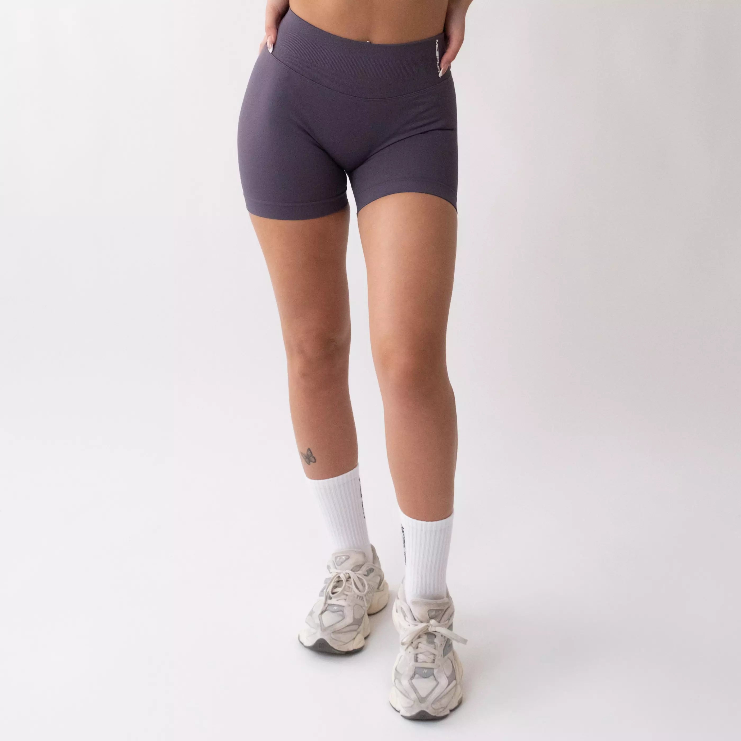 Shorts sportivi grigi da donna indossati con fascia alta in vita, morbidi ed elasticizzati.