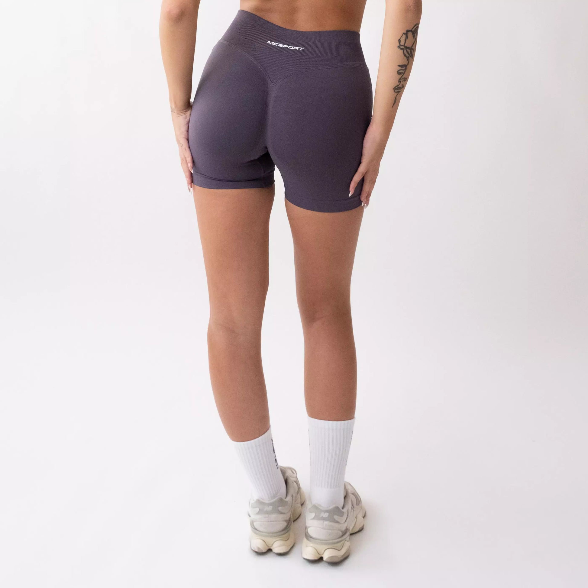 Shorts sportivi grigi da donna indossati con fascia alta in vita, morbidi ed elasticizzati.