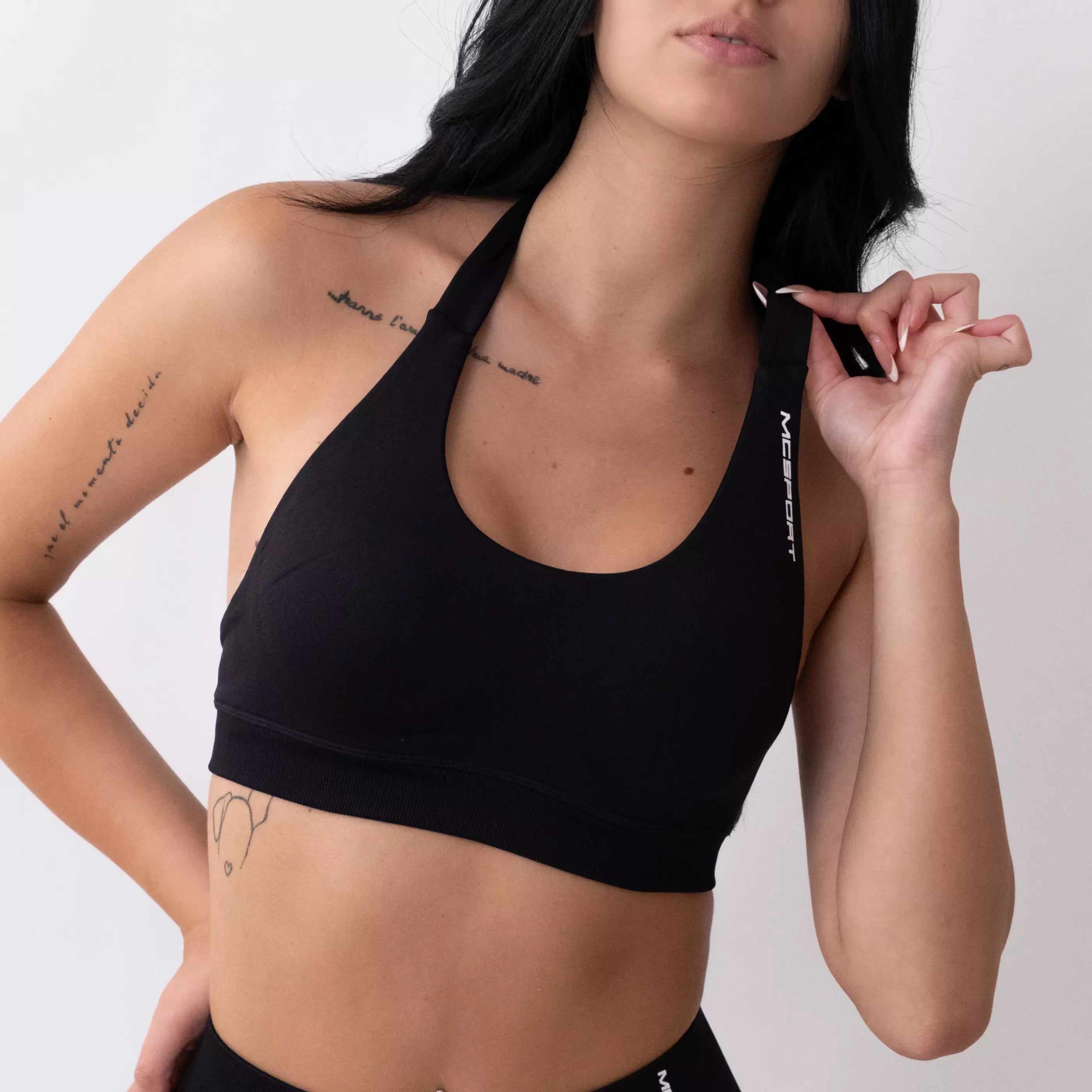 Top sportivo nero da donna indossato dal design essenziale e confortevole, ideale per fitness, palestra, yoga e pilates.