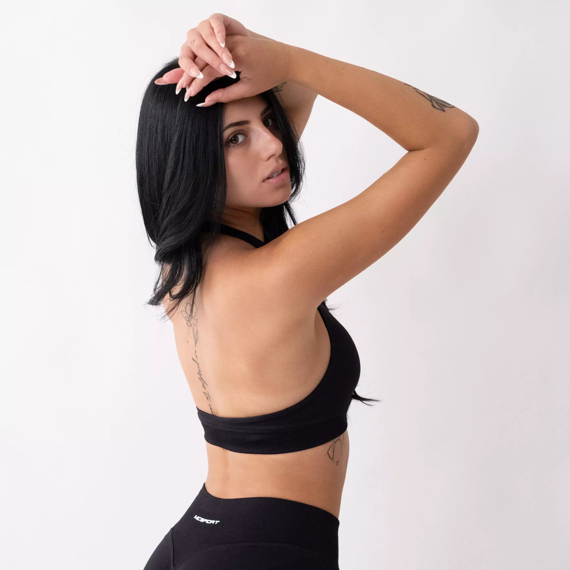 Top sportivo nero da donna indossato dal design essenziale e confortevole, ideale per fitness, palestra, yoga e pilates.