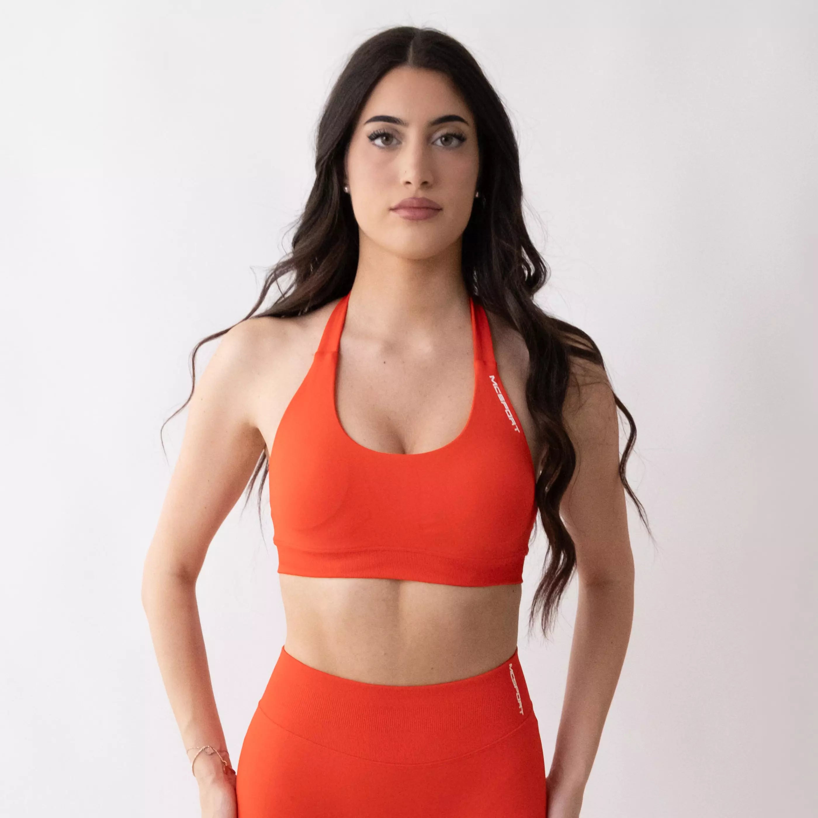Top sportivo color corallo da donna indossato dal design essenziale e confortevole, ideale per fitness, palestra, yoga e pilates.