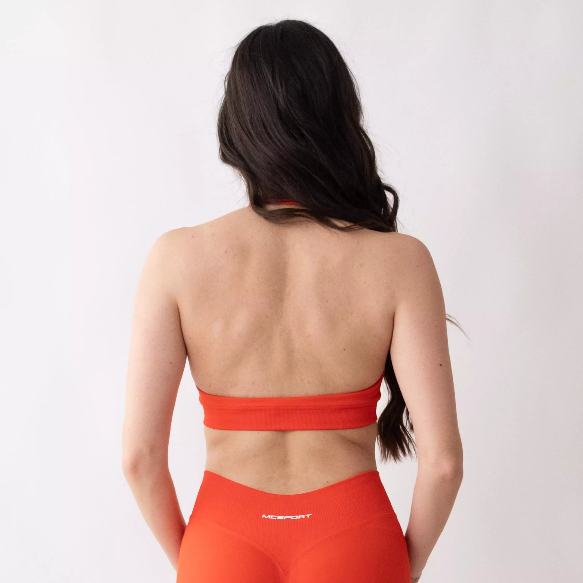 Top sportivo color corallo da donna indossato dal design essenziale e confortevole, ideale per fitness, palestra, yoga e pilates.