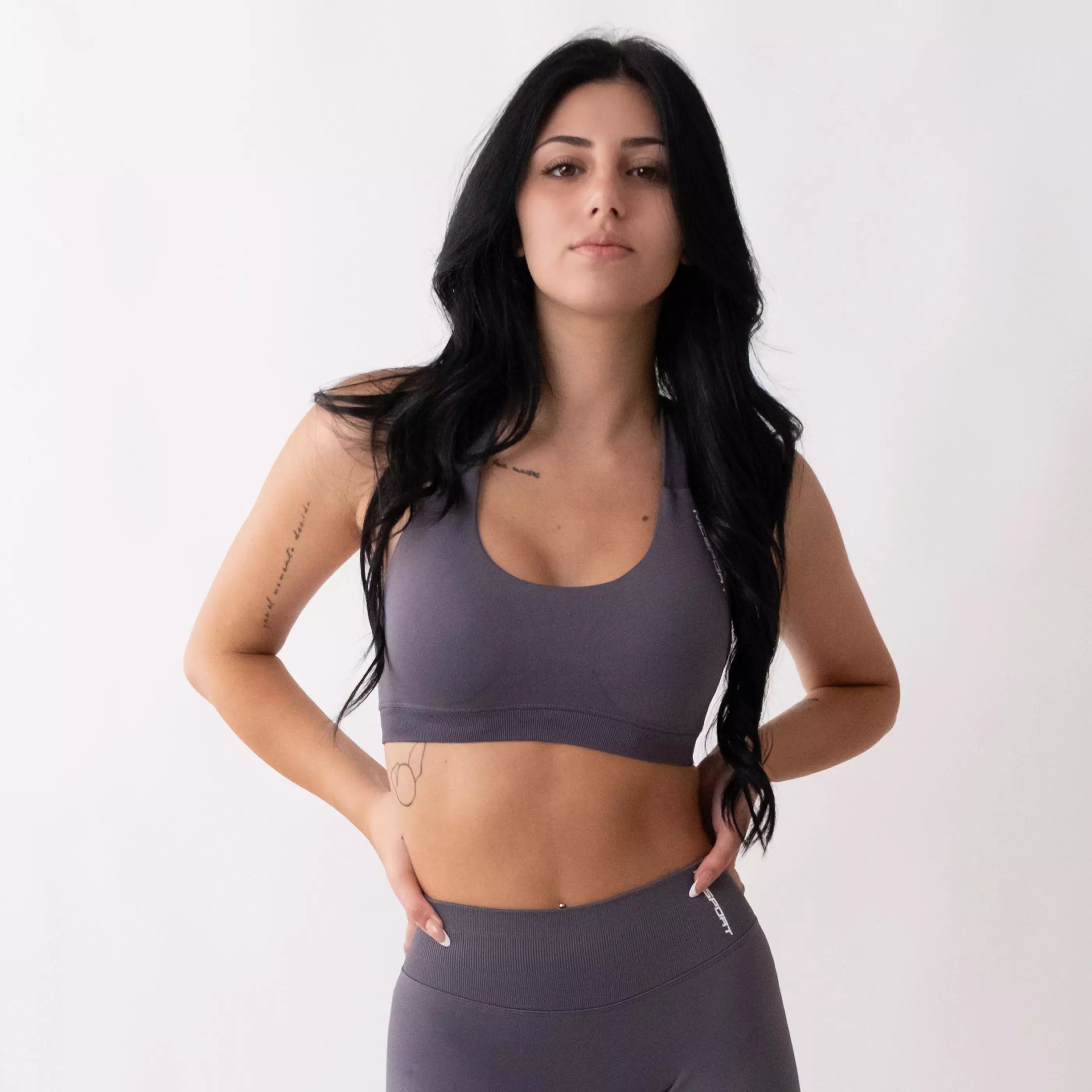 Top sportivo grigio da donna indossato dal design essenziale e confortevole, ideale per fitness, palestra, yoga e pilates. 