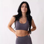 Top sportivo grigio da donna indossato dal design essenziale e confortevole, ideale per fitness, palestra, yoga e pilates. 