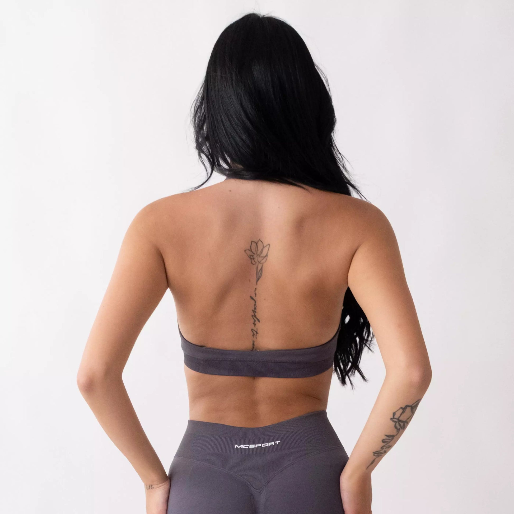 Top sportivo grigio da donna indossato dal design essenziale e confortevole, ideale per fitness, palestra, yoga e pilates. 