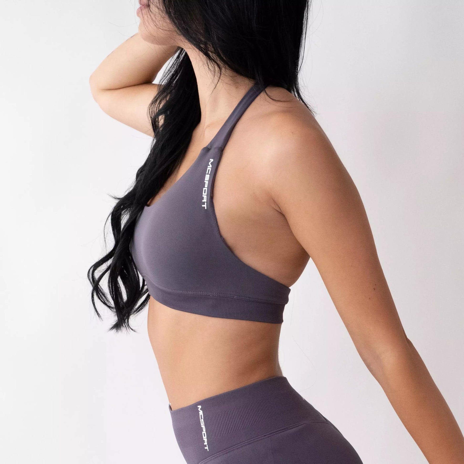 Top sportivo grigio da donna indossato dal design essenziale e confortevole, ideale per fitness, palestra, yoga e pilates. 