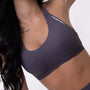 Top sportivo grigio da donna indossato dal design essenziale e confortevole, ideale per fitness, palestra, yoga e pilates. 
