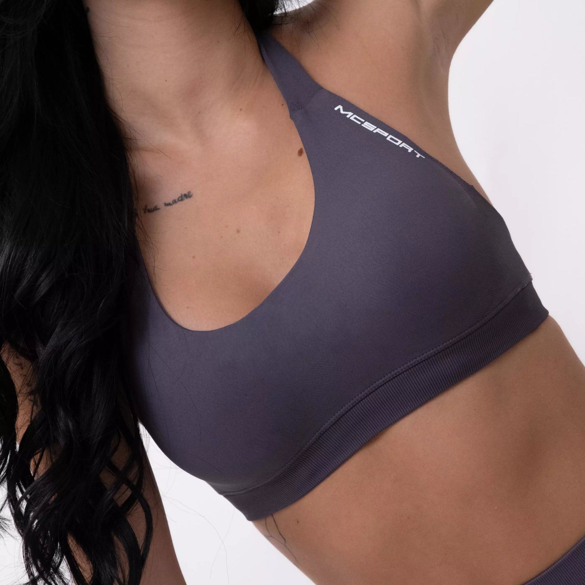 Top sportivo grigio da donna indossato dal design essenziale e confortevole, ideale per fitness, palestra, yoga e pilates. 