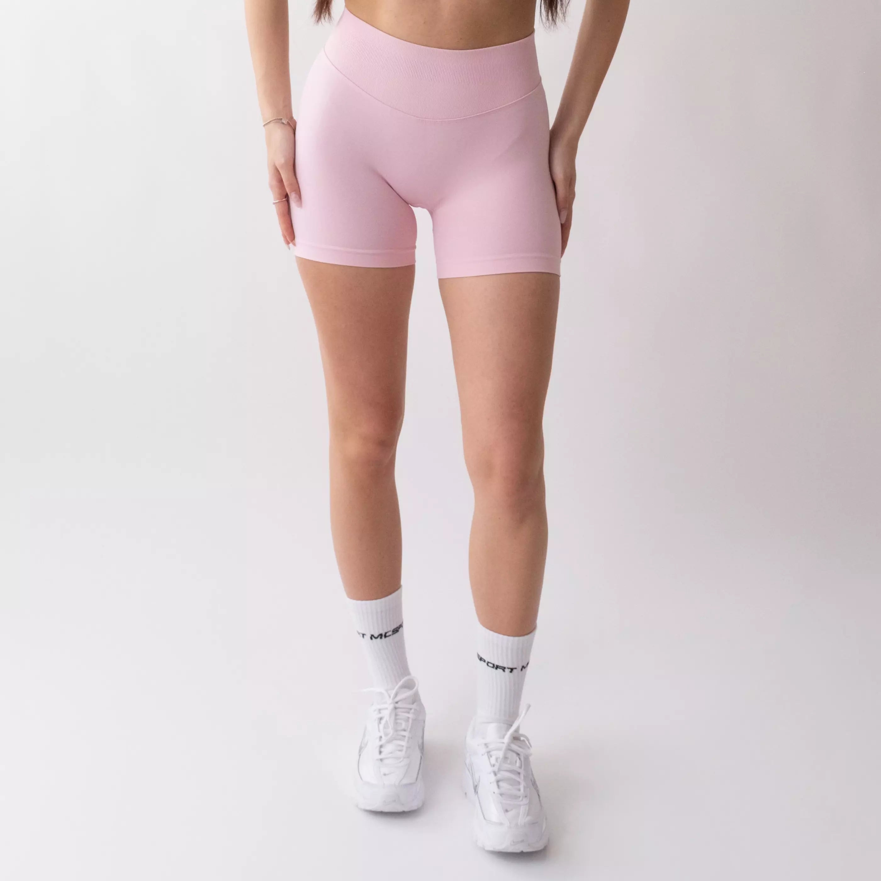 Shorts sportivi rosa da donna indossati con fascia alta in vita, morbidi ed elasticizzati.