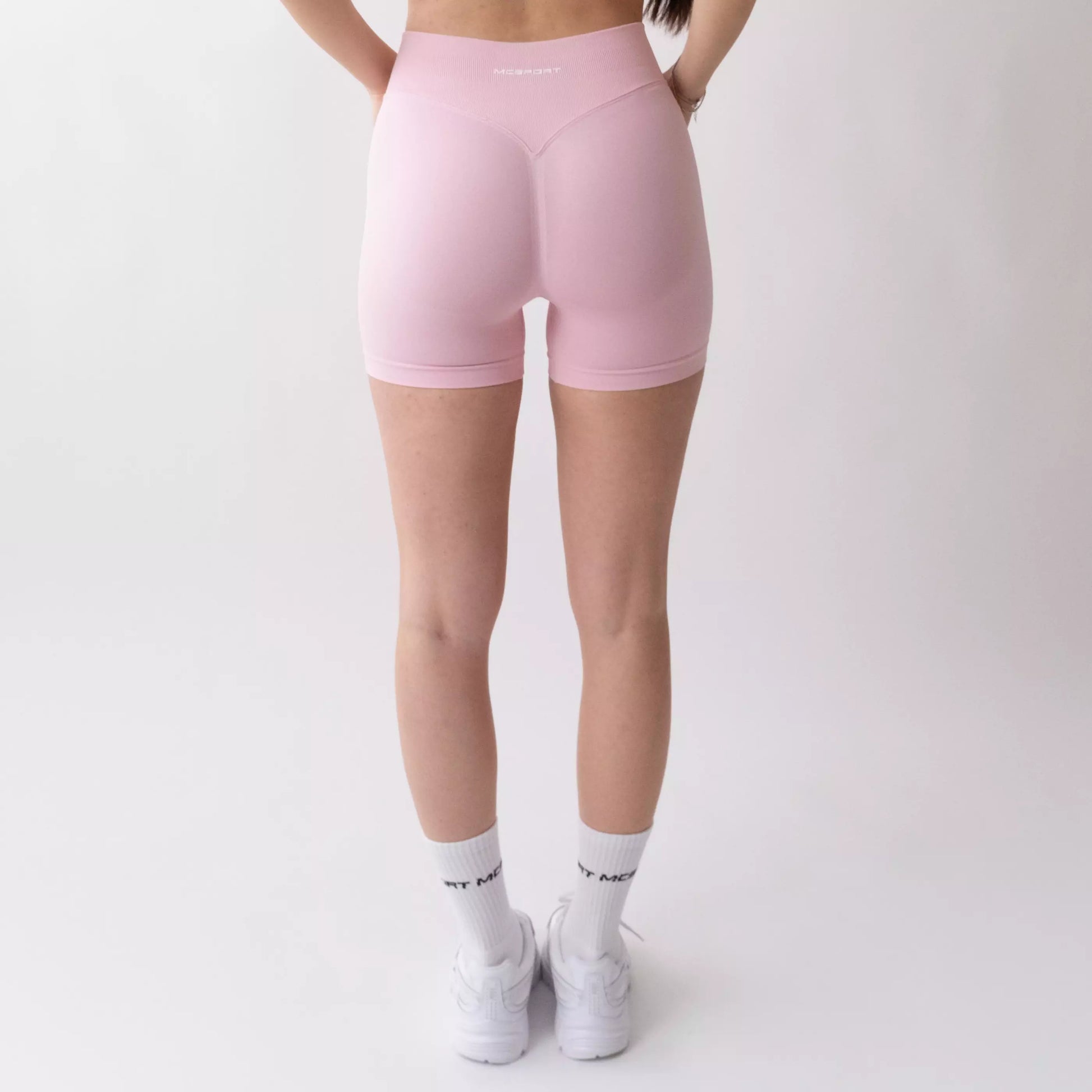 Shorts sportivi rosa da donna indossati con fascia alta in vita, morbidi ed elasticizzati.