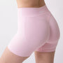Shorts sportivi rosa da donna indossati con fascia alta in vita, morbidi ed elasticizzati.