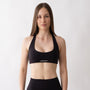 Top sportivo nero da donna indossato con schiena olimpionica: tessuto elasticizzato, supporto confortevole e libertà di movimento per fitness, yoga, pilates e allenamenti.