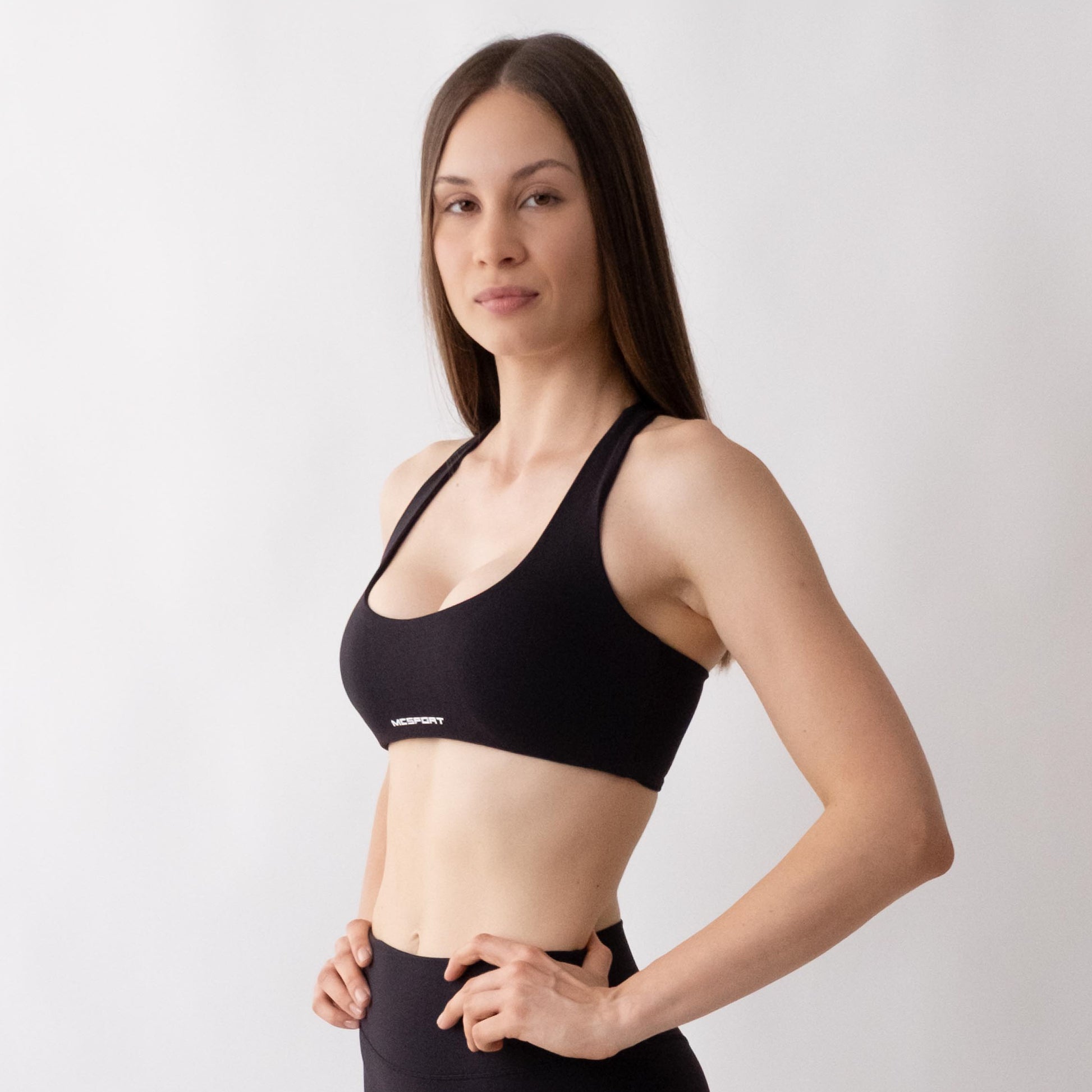 Top sportivo nero da donna indossato con schiena olimpionica: tessuto elasticizzato, supporto confortevole e libertà di movimento per fitness, yoga, pilates e allenamenti.